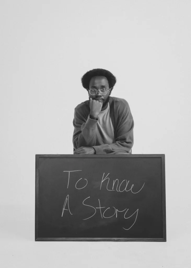 Mike Bosco black and white portrait sitting with chalk board leaning on legs